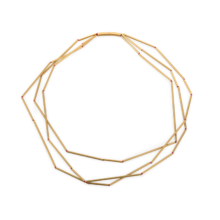 Three-row chain made of differently long and gold-colored aluminum tubes. The tubes are knotted on red pearl silk. The knots appear like red pearls in the gaps. The chain is closed by a cylindrical magnetic clasp.