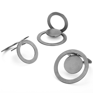 Drei Kreisringe aus Edelstahl. Jeder Ring ist aus einem Kreis gefertigt. Das Blech wurde hierzu zweimal im Kreisbogen geschnitten, wobei die Kreise nicht durchgeschnitten sind, sondern ein 5mm breiter Steg bleibt. Der mittlere Ring ist rechtwinklig abgeknickt, bildet den Ring, durch den der Finger gesteckt werden kann. Der Äußere Kreisring und der innere Kreispunkt ergeben das Zierteil, den Ringkos.