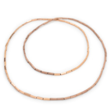 A long chain is placed twice in two circles. It is threaded from rosé colored small blocks and half shiny and half polished.