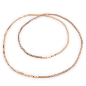 A long chain is placed twice in two circles. It is threaded from rosé colored small blocks and half shiny and half polished.