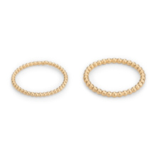 Two rings of different sized beads lie side by side. The beads of the left ring have a diameter of 1.5mm, those of the right ring of 2mm diameter. Both are made  of gold plated silver.
