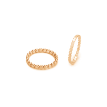 Two fine, but differently strong gold-plated rings next to each other. The thicker ring lies flat, the thinner ring is placed to the right. The pattern describes many points that sit evenly and in line next to each other.
