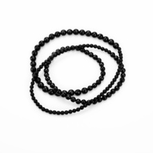 Three differently sized and faceted onyx balls are drawn into a long chain. This is placed in loops, whereby the balls of one size are always one behind the other.