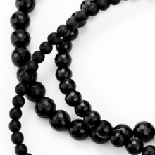 Close-up view of the three different sized faceted balls of the onyx chain. One part of the balls is shiny, the other part is matt.