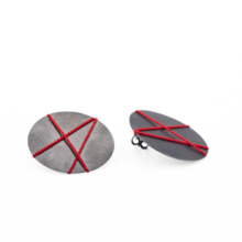 30mm discs made of blackened silver plate as ear studs. A red silk thread is stretched across the surface in three intersecting lines, creating a graphic pattern