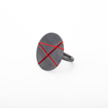 Ring-big-disk-schwarz-rot Ring mit großer 30mm Zierplatte aus geschwärztem Silber. Die Platte ist mit drei roten sich überschneidenden Linien aus Seide bespannt, was ein grafisches Muster erzeugt