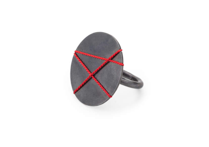 Ring with large 30mm decorative plate made of blackened silver. The plate is covered with three red, overlapping lines of silk, which creates a graphic pattern