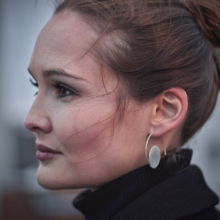 creole-SUN Frau im Profil mit Silberohrschmuck. Eine Silberscheibe von 22mm Durchmesser scheint fast zu schweben. Fast wie eine Spirale läuft ein Runddraht um die Scheibe, welcher auch gleich die Funktion erfüllt. Der Draht wird wie bei einer Creole durch das Ohrloch gesteckt.