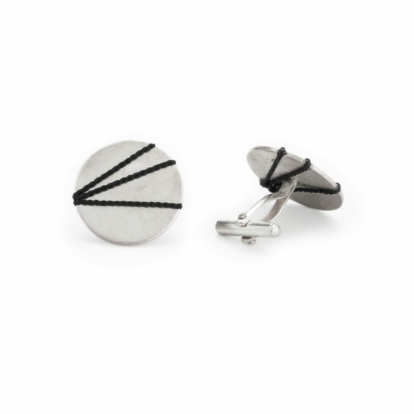 Cufflinks made from sterling silver. The decorative plate measures 19mm in diameter and is covered with a black silk thread. The silk thread creates a graphic pattern of three lines. On the back is the mechanism for fastening the buttons.