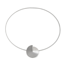 Silver pendant the size of a coin on a wire necklace. The circular disc is cut to the center and bent up a bit. This creates a slit and a three-dimensional effect