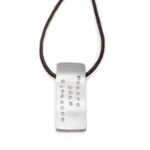 Rectangular pendant, approx. 15mm wide, made of silver and on a leather strap. The pendant is embossed with three words from top to bottom and is slightly curved in itself.
