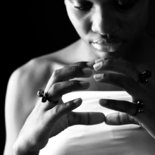 div_ringe_globulus Nahaufnahme von Frauenhänden, die mit drei geschwärzten Silber-Ringen geschmückt sind. Die Ringe sind jeweils mit einer kleinen Silberkugel und einer Onyx- oder Rauchqaurzkugel besetzt.