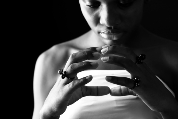 Nahaufnahme von Frauenhänden, die mit drei geschwärzten Silber-Ringen geschmückt sind. Die Ringe sind jeweils mit einer kleinen Silberkugel und einer Onyx- oder Rauchqaurzkugel besetzt.