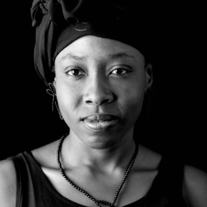 Frau mit Kette und Ohrschmuck aus kleinen Onyxperlen. Diese sind ähnlich wie Pflanzenranken zu unterschiedlichen Schlaufen geknüpft.