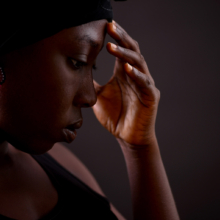 ohrschmuck_tendril_pink Frau im Profil mit Ohrschmuck aus kleinen Onyx- und Karneolperlen. Die Perlen sind zu zwei sich überschneidenden Schlaufen auf Nylon geknüpft.