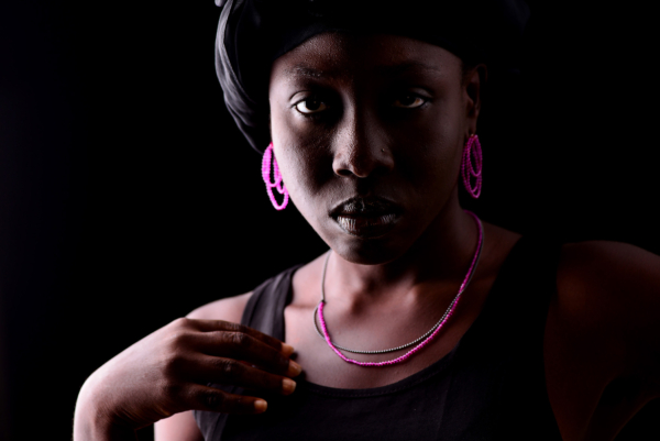 Portrait of a woman wearing pink earrings and a black-pink necklace. The necklace is double-stranded: one with Rubellite and one with blackened silver beads. The earring consists of three interlocking loops of Rubellite on nylon and is equipped with a silver stud.