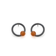 ohrstecker_sphere_karneol Ring-Ohrstecker aus geschwärztem Silber, mit einer einzelnen orangefarbenen Karneolkugel besetzt.
