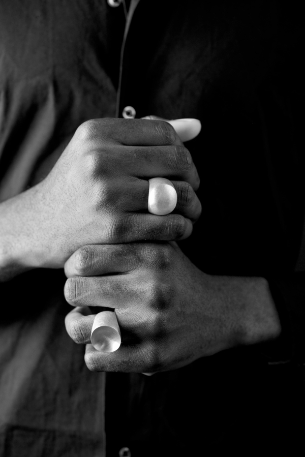 ring_connected_konvex+konkavrund Männerhände, die zwei fette Siegelringe mit aus Silber tragen. Beide Siegelplatten sind kreisrund. Die eine konvex, die andere konkav gewölbt, so dass sie auch ineinander passen.