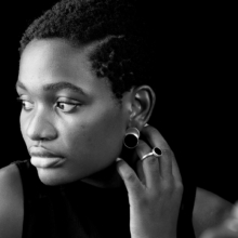 ring_laminam_onyx2 Eine Frau trägt Ohrstecker und einen Ring aus Silber, verziert mit runden Onyxsteinen.