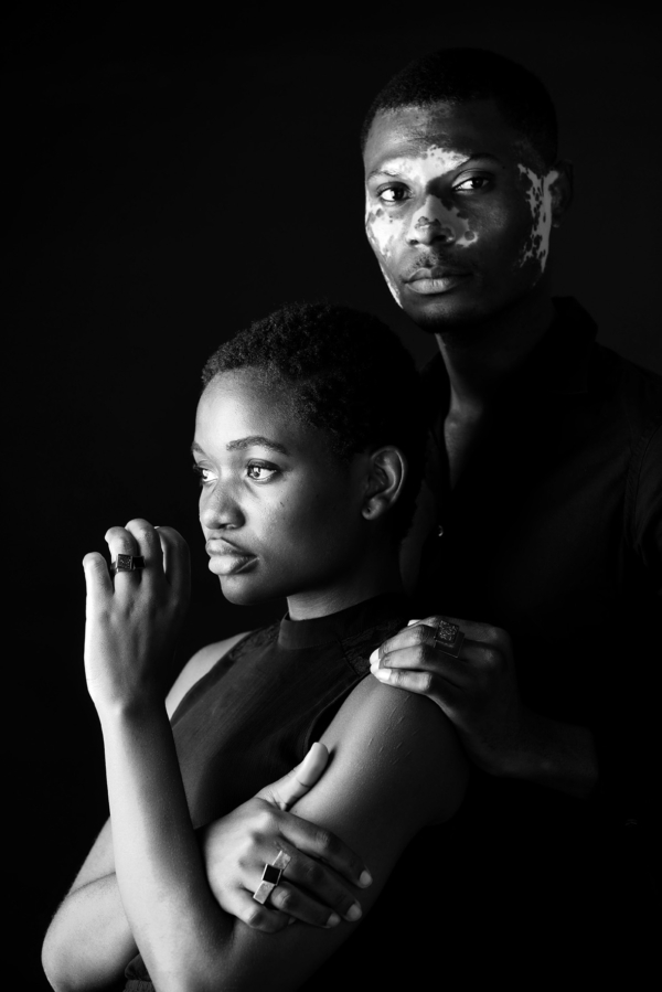 ringe_carre_ring_COUBO Ein Mann steht hinter einer Frau. Beide tragen eckige, schwarze Ringe mit quadratischen Onyxsteinen besetzt.