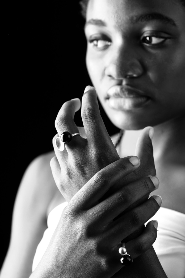 ringe_globulus Nahaufnahme einer Frau, die zwei Ringe aus Sterlingsilber trägt. Einer mit einer Silberschale und einer Onyxkugel, der andere mit einer Silber- und einer facettierten Onyxkugel.