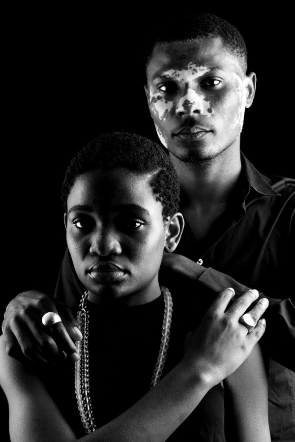 ringe_paar_konkavkonvex_rund Ein Mann und eine Frau stehen hintereinander. Beide tragen Siegelringe mit runder Siegelplatte. Der Männerring ist konvex, der Frauenring konkav gewölbt. Die Frau trägt eine Kette aus Bergkristallkugeln.