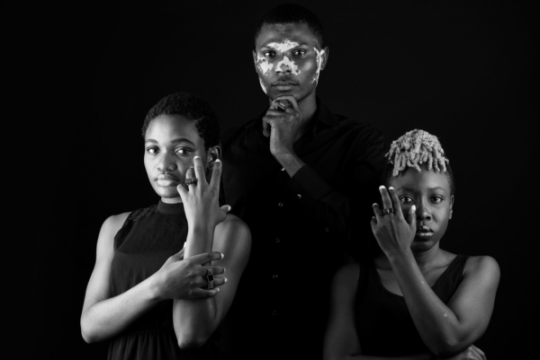 ringgruppe_carre+CUBO Ein Mann und zwei Frauen stehen in einer Gruppe und tragen eckige Ringe mit quadratischen Onyxsteinen besetzt.