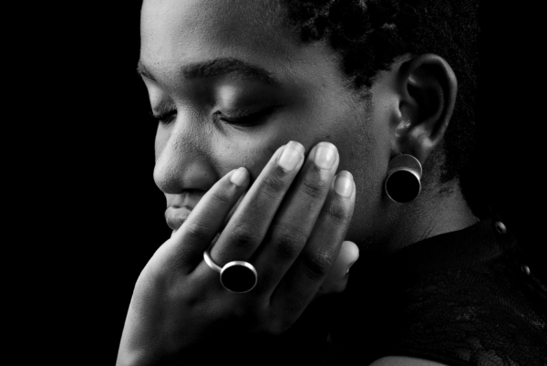 ring+ohrst_laminam_onyx_close Close-up of hand and head of woman wearing ring and earring made of silver, decorated with large onyx discs.